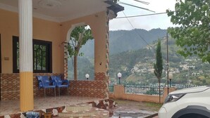 Un espacio de estar al aire libre cubierto con sillas, piso de baldosas y vistas a un paisaje montañoso.