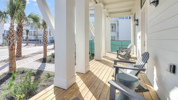 A covered outdoor area with wooden flooring, white pillars, and seating. - Boardwalk Breeze 109 Sou (Port Aransas)