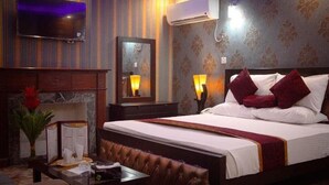 A hotel room with a bed, bedside lamps, a flat-screen TV, an air conditioning unit, a mirror, and a table with a menu. - Mall View Hotel Gulberg (Lahore)