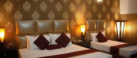 A hotel room with two beds, a patterned wallpaper, and bedside lamps.