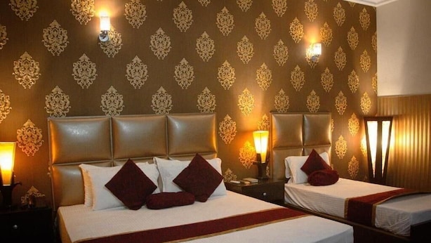 A hotel room with two beds, a patterned wallpaper, and bedside lamps. - Mall View Hotel Gulberg (Lahore)