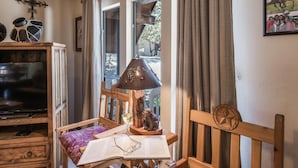 Eine gemütliche Leseecke mit einem Holzstuhl, einem Tisch mit einem Buch und einer Brille, einer Lampe und einem Fernseher auf einer Holzkommode.