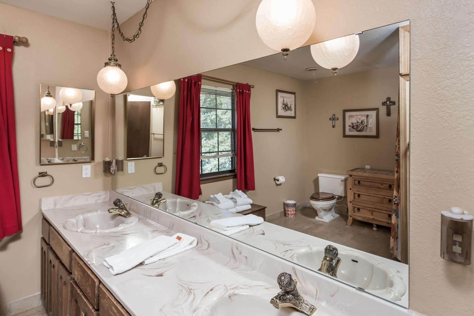Een badkamer met een grote spiegel, twee wasbakken, een toilet en een douchehoek.