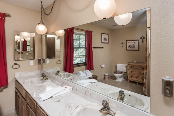 A bathroom with a large mirror, two sinks, a toilet, and a shower area. - Cowboys Indians And Outlaws By Vtrips (Ruidoso)