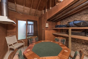 A wooden interior with a round table, plaid chairs, a bench, and a wall-mounted shelf with luggage. - Cowboys Indians And Outlaws By Vtrips (Ruidoso)