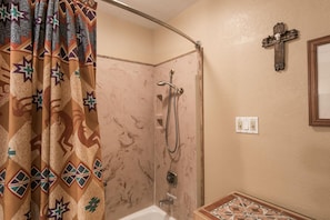 A bathroom with a shower, a sink, a mirror, and a wall-mounted cross. - Cowboys Indians And Outlaws By Vtrips (Ruidoso)