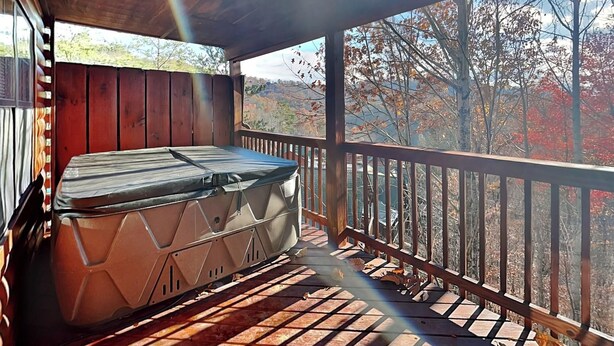 Ein Whirlpool auf einer Holzterrasse mit Blick auf Herbstbäume.