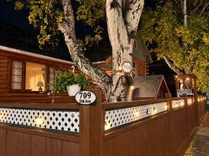 Una cabaña de madera con un cartel que dice '709 5th Ave' y una valla con celosía.