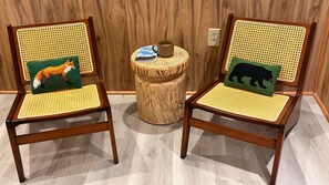 Dos sillas de madera con respaldo y asiento tejidos, cada una con un cojín que presenta un diseño de zorro y oso.