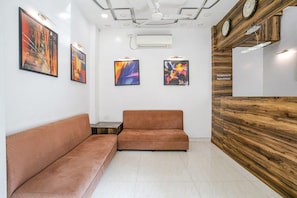 A reception area with a wooden reception desk, two sofas, and abstract artwork on the walls. - Fabhotel Sai Plaza Executive (Chhatrapati Sambhajinagar)