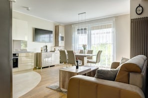Una sala moderna con un sofá, una mesa de comedor y una zona de cocina con un televisor.