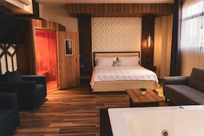 A hotel room with a large bed, two sofas, a wooden floor, and a red door. - Hotel San Carlos (La Barca)