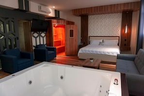 A hotel room with a large bathtub, two beds, a TV, and a seating area. - Hotel San Carlos (La Barca)