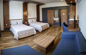 A hotel room with two beds, a blue sofa, a wooden bench, and a mirror. - Hotel San Carlos (La Barca)