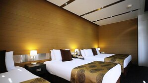 Een hotelkamer met drie bedden, houten lambrisering en een modern plafondontwerp.