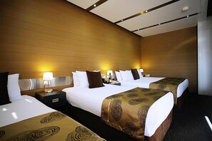 Ein Hotelzimmer mit drei Betten, Holzwandverkleidung und einem modernen Deckenstil.