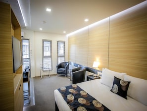 Ein Hotelzimmer mit Bett, Schreibtisch, Stuhl und Fernseher.