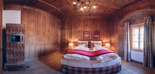 Una habitación de madera con una cama, dos lámparas, una araña y un armario.