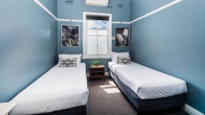 Een kamer met twee eenpersoonsbedden, een raam en twee foto's aan de muur.