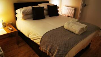 A neatly made bed with white linens, a dark headboard, and a patterned throw blanket.