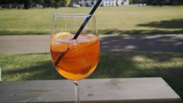 A glass of amber-colored beverage with a straw on a wooden table.
