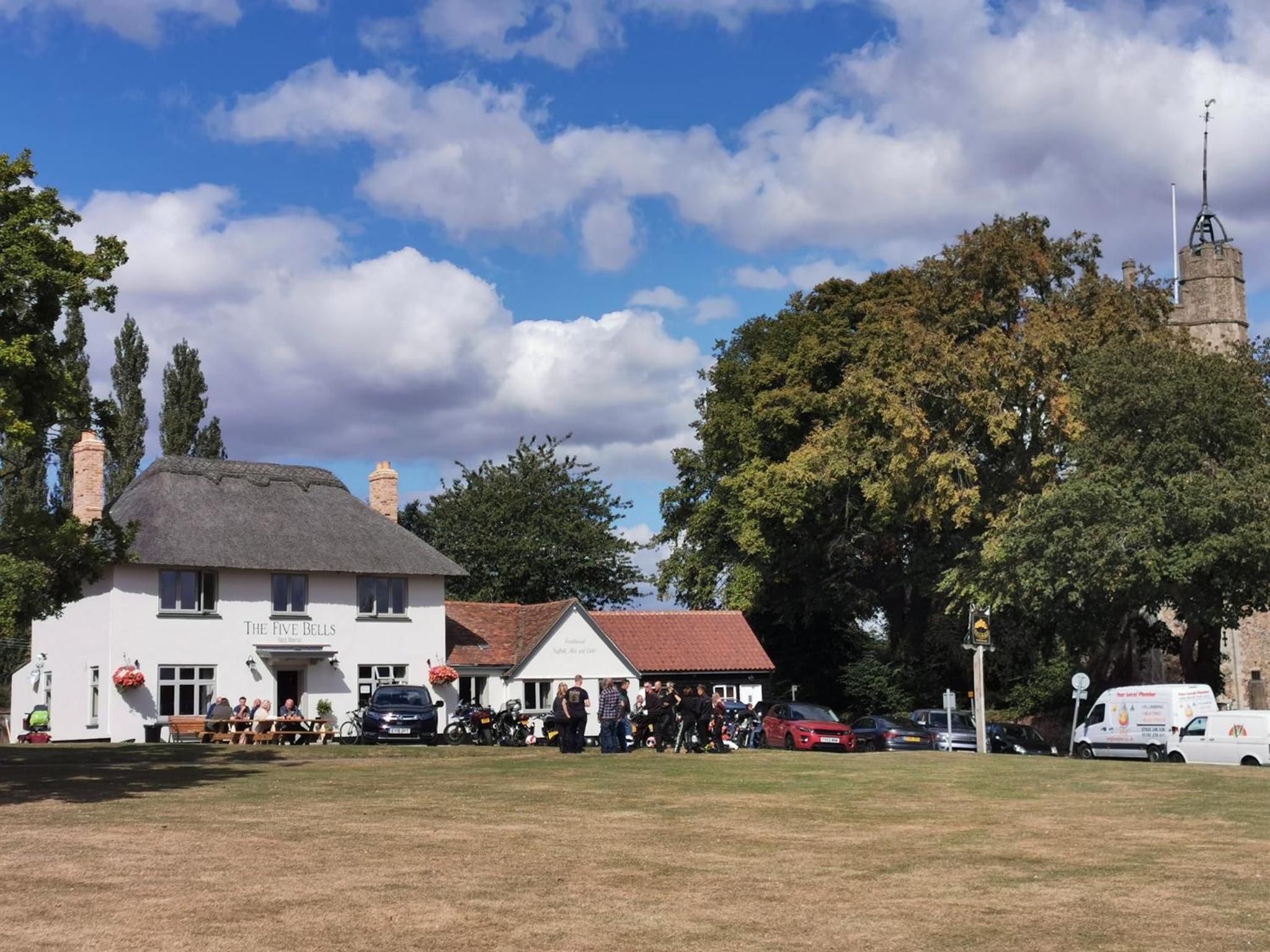 A traditional building with a thatched roof, a white exterior, and a sign reading 'The Five Bells.'