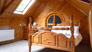A wooden attic bedroom with a sloped ceiling, a bed with a wooden headboard, a dresser, and a skylight. - The Elmsleigh Suite At Claremont Hotel (Nottingham)