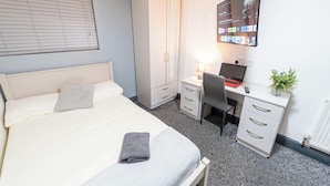 A bedroom with a bed, a desk, a chair, a wardrobe, and a wall-mounted TV. - Charming Studio In Birmingham (Birmingham)