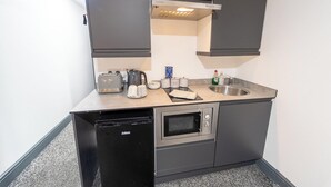 A compact kitchenette with a built-in dishwasher, a microwave, a toaster, a kettle, and a sink. - Charming Studio In Birmingham (Birmingham)