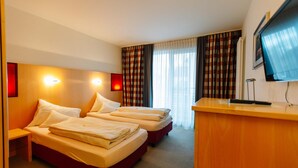 A hotel room with two beds, a desk, and a television. - Landhotel Gasthof Drexler Gbr (Fuerstenfeldbruck)