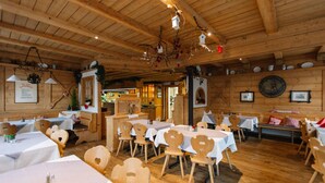 A rustic wooden interior with multiple tables and chairs, wooden beams on the ceiling, and various decorations. - Landhotel Gasthof Drexler Gbr (Fuerstenfeldbruck)