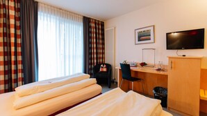 A hotel room with two beds, a desk, a chair, a television, and a radiator. - Landhotel Gasthof Drexler Gbr (Fuerstenfeldbruck)