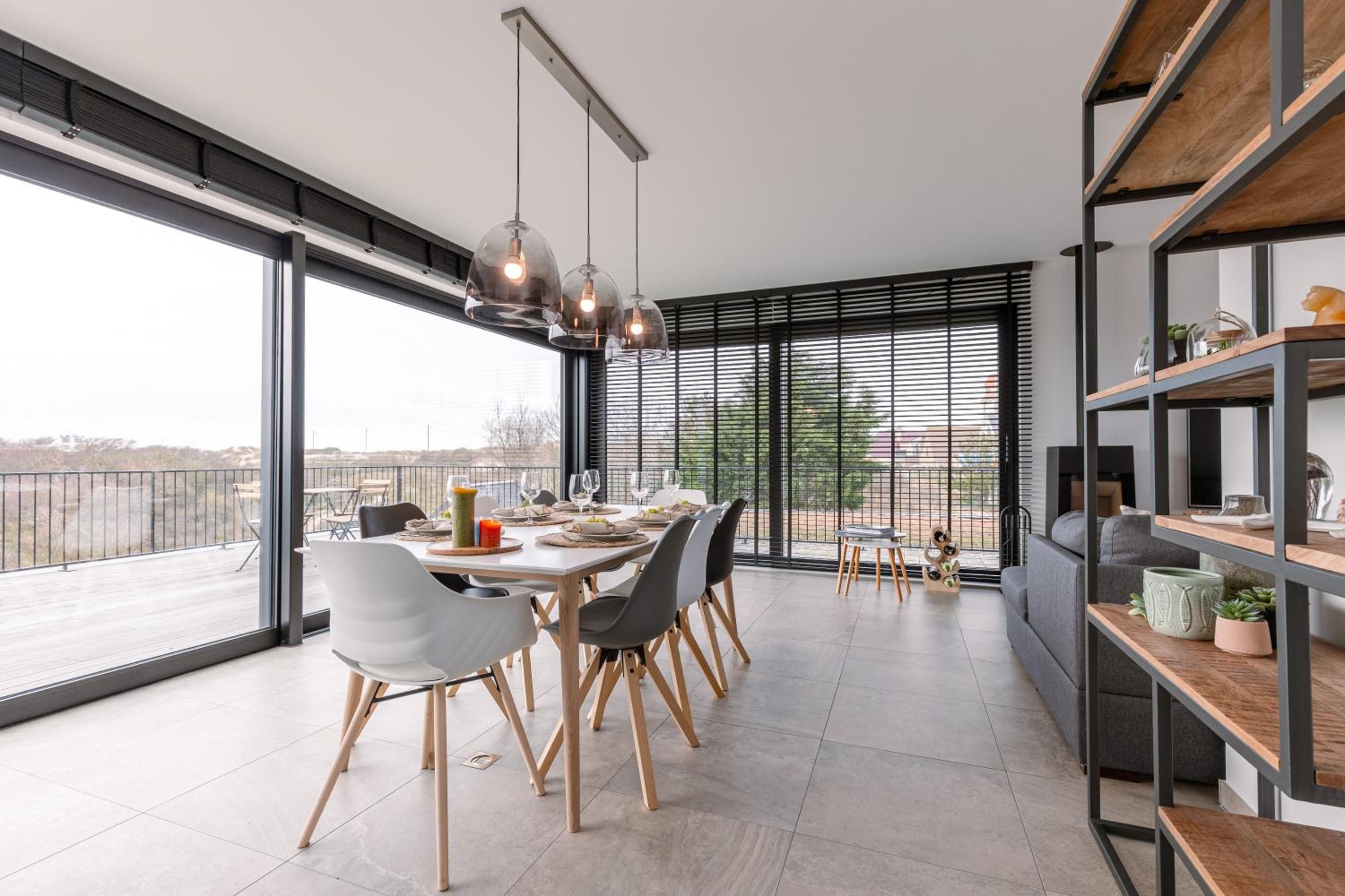 Een moderne eetruimte met een grote tafel, stoelen en hanglampen.