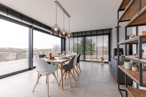 Uma sala de jantar moderna com uma mesa grande, cadeiras e iluminação pendente.