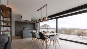 Una cocina moderna con comedor, ventanas amplias y vista a una casa.