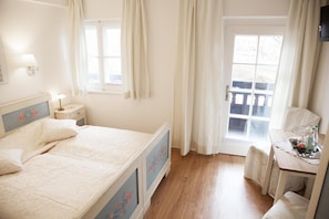 A bedroom with a bed, bedside table, lamp, and a window with curtains. - Hotel Garni Georgenhof Adults Only (Rimsting)