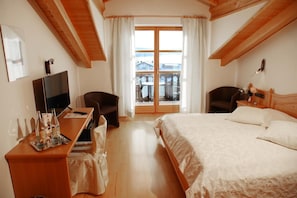 A hotel room with a bed, a desk, a chair, a TV, and a window with curtains. - Hotel Garni Georgenhof Adults Only (Rimsting)