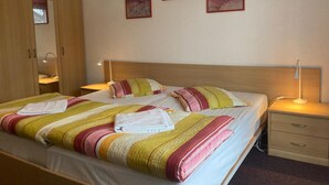 Habitació d'hotel amb llit, taules de nit, armari i tres quadres penjats a la paret.