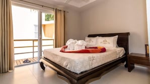 Een hotelkamer met een bed, nachtkastje, plafondventilator en een schuifdeur.