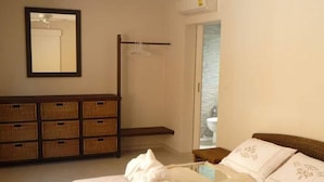 Een slaapkamer met een bed, een plafondventilator, een kledingkast en een zichtbare badkamer door een geopende deur.