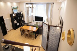 A modern living room with a dining area, a TV, and a bookshelf.