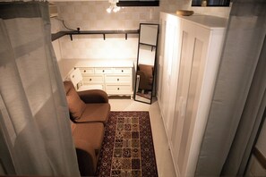A compact bathroom with a white vanity, a brown sofa, and a patterned rug.