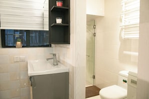 A modern bathroom with a glass shower enclosure, a white sink, and a toilet. - Innocondo Extended Stay Changning Yuyuan (Shanghai)