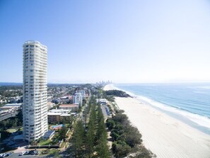 A coastal cityscape with a prominent high-rise hotel, beachfront, and a distant city skyline. - Burleigh Surf 18th Floor Spectacular Ocean Views (Gold Coast)