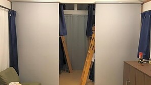 Et værelse med køjeseng, et lille bord med en servietæller og et skab med en flaske ovenpå.