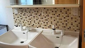 A bathroom with two sinks, a mirror, and a tiled backsplash. - Kakunodate Guest House Choux (Senboku)