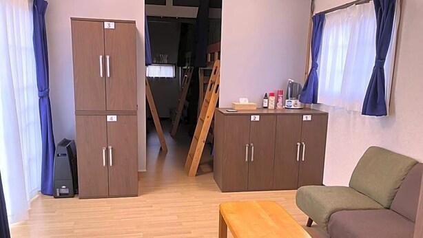 Et værelse med en træbænk, en sofa og en garderobe med nummererede rum.