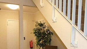 A staircase with white railings and a potted plant at the bottom. - Ladiges Gasthof (Holm)