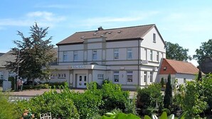 A multi-story building with a flat roof and a sign indicating it is a hotel. - Ladiges Gasthof (Holm)