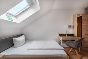 A compact room with a skylight, a bed, a desk, and a chair. - Hotel Glas Schwarzwald (Fluorn)